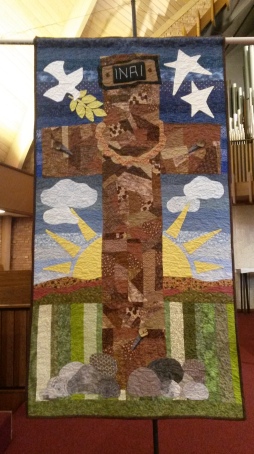 A cross that is lifted on a banner that is lifted up. 